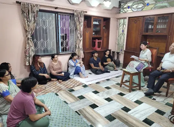 Participants seated on the floor around a reader in a home session