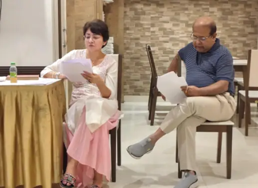 Two readers holding scripts during a rehearsal